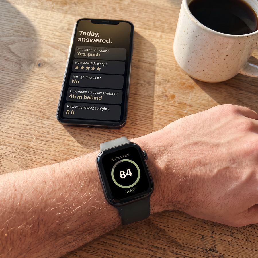 A wrist wearing Apple Watch reading 84 ready, next to an iPhone with the morning's answers and a cup of coffee